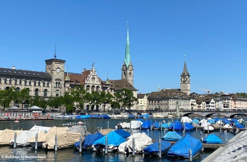 Small boats moored on River Limmat in Zurich with Old Town buildings in the background