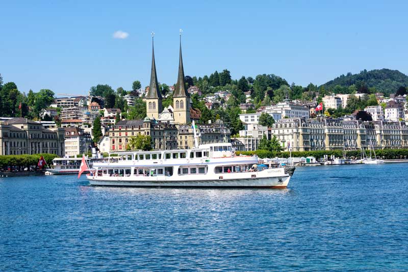 Cruise boat on Lake Lucerne with Hofkirche's twin towers behind. 