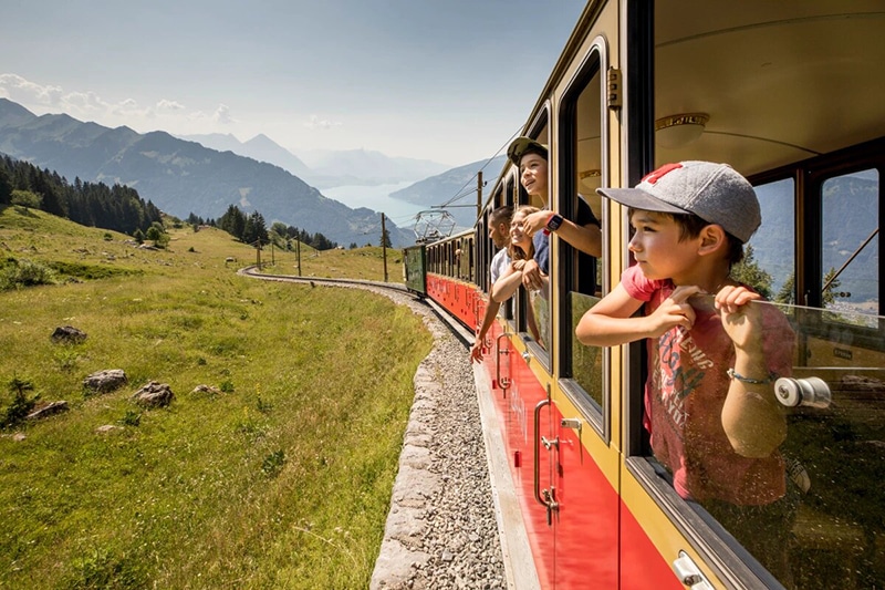 Children look out the open windows of the Schynige Platte mountain train in Switzerland.